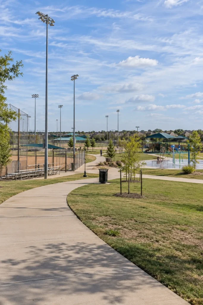 Walking trail past lighted ball fields, a splash pad and a playground at a large North Texas city park